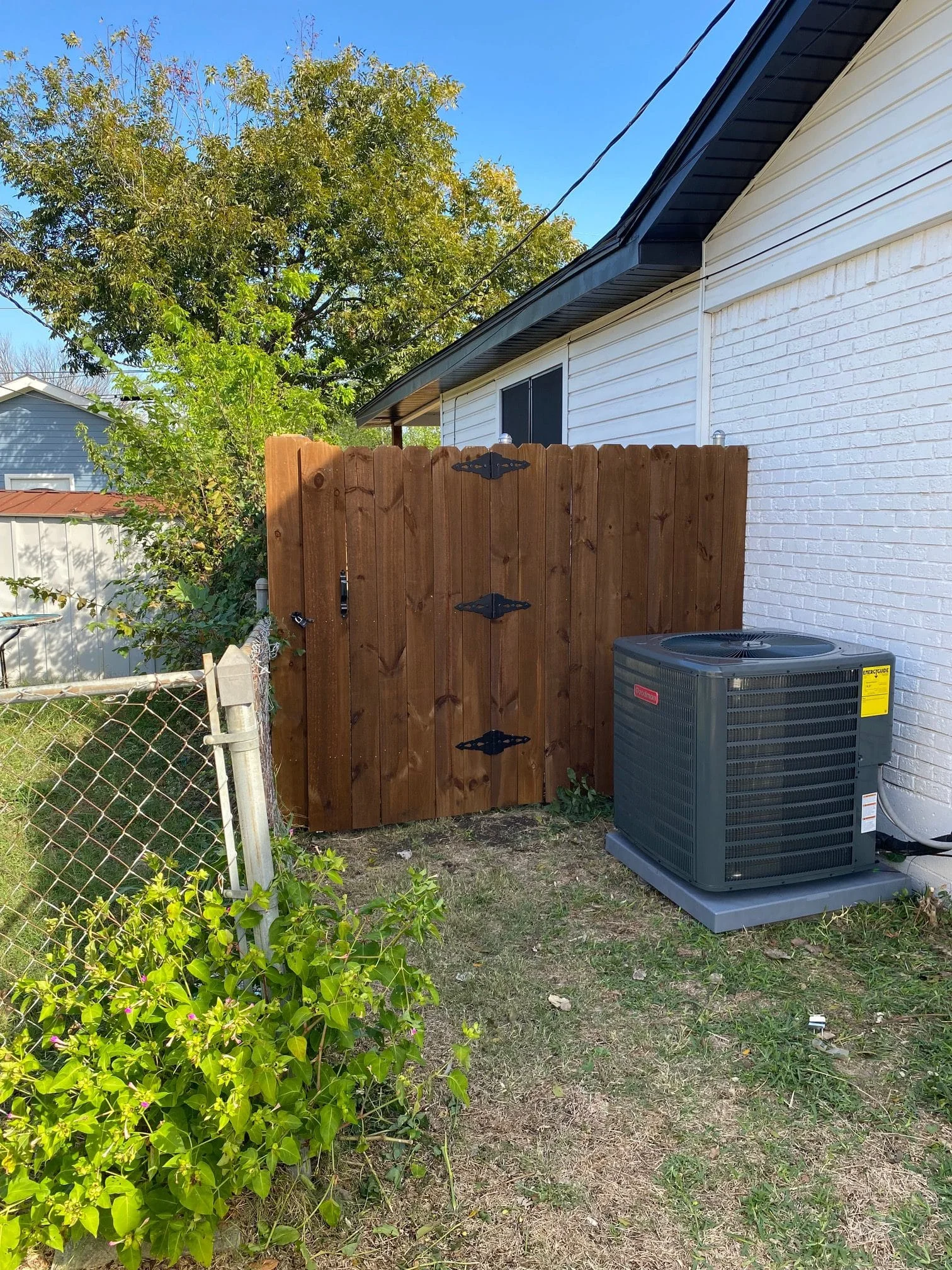 Full view of the installation of a Goodman condenser with new condenser pad and anti-tampering service port locking caps in Desoto, Texas