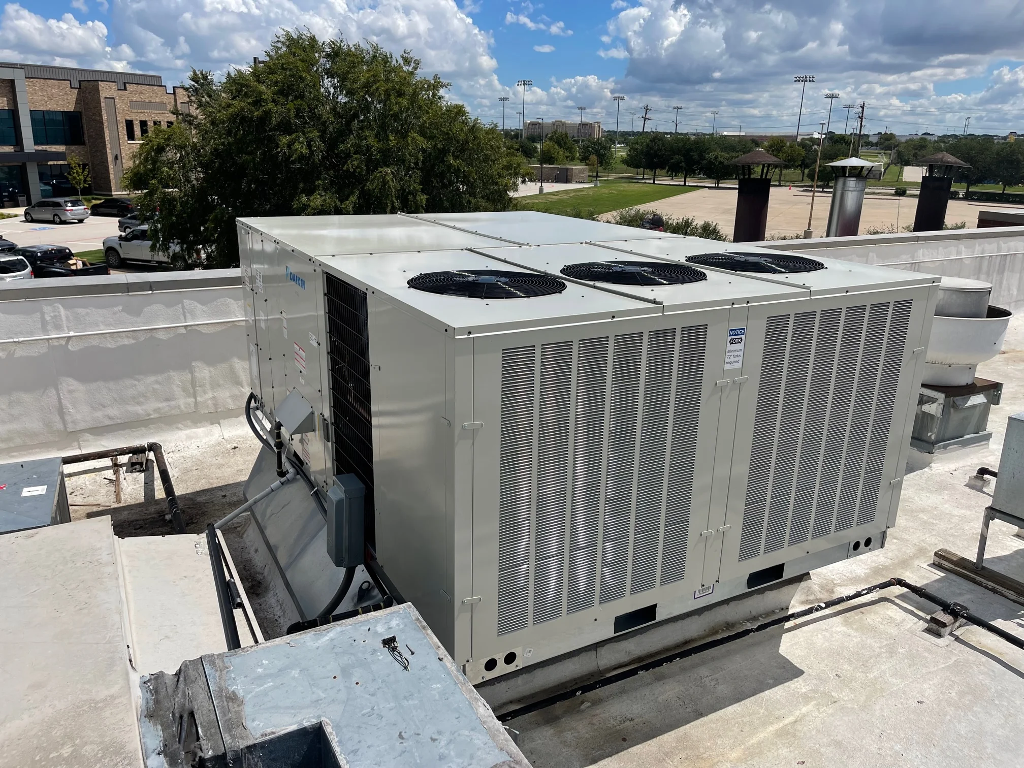 Service panel side view of completed installation Daikin 20 ton commercial rooftop gas package unit with fabricated sheet metal curb adapter