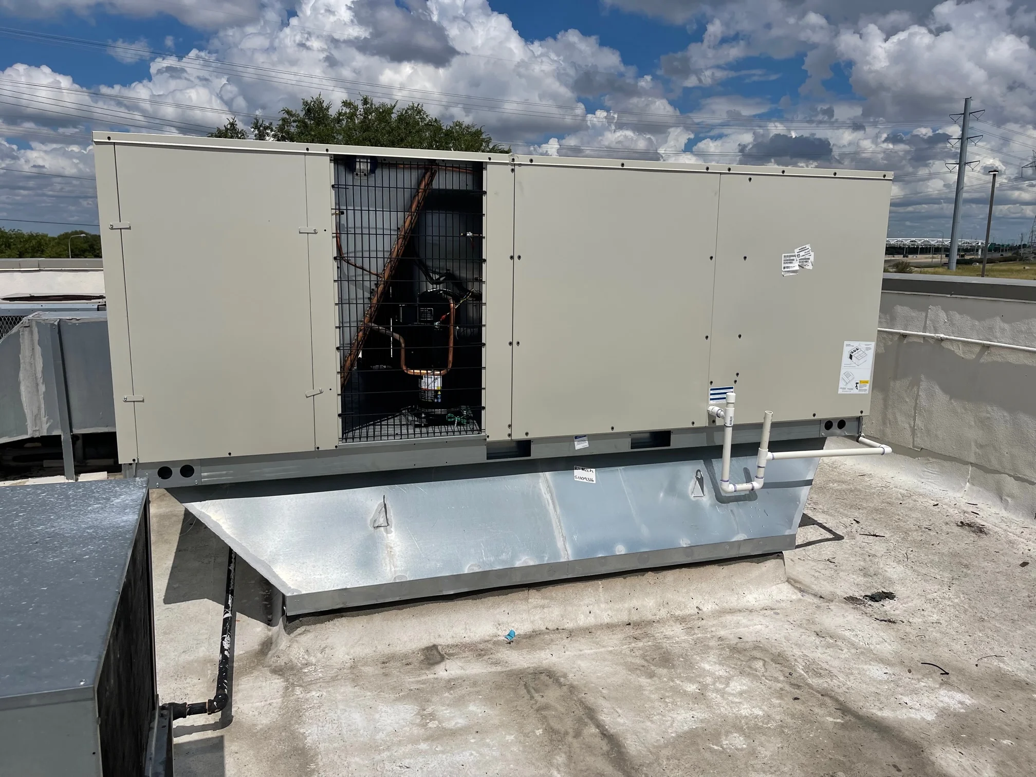 Backside view of completed installation Daikin 20 ton commercial rooftop gas package unit with fabricated sheet metal curb adapter